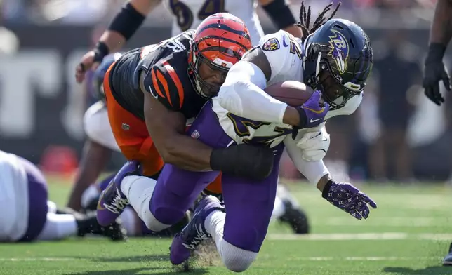 Baltimore Ravens running back Derrick Henry (22) takes a hit from a Cincinnati Bengals defensive tackle Kris Jenkins Jr. during the first half of an NFL football game, Sunday, Oct. 6, 2024, in Cincinnati. (AP Photo/Carolyn Kaster)