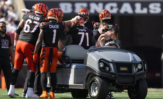 Cincinnati Bengals players approach offensive tackle Amarius Mims as he is carted off the field during the second half of an NFL football game against the Baltimore Ravens, Sunday, Oct. 6, 2024, in Cincinnati. (AP Photo/Carolyn Kaster)