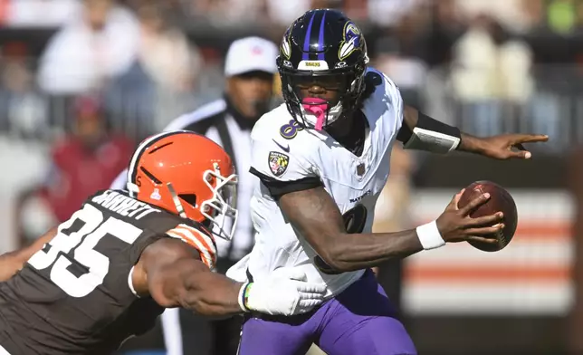 Baltimore Ravens quarterback Lamar Jackson (8) escapes from Cleveland Browns defensive end Myles Garrett (95) during the second half of an NFL football game in Cleveland, Sunday, Oct. 27, 2024. (AP Photo/David Richard)