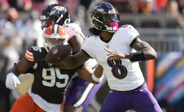 Baltimore Ravens quarterback Lamar Jackson (8) throws in from top Cleveland Browns defensive end Myles Garrett (95) during the first half of an NFL football game in Cleveland, Sunday, Oct. 27, 2024. (AP Photo/Sue Ogrocki)