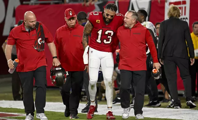 Tampa Bay Buccaneers wide receiver Mike Evans (13) is helped off the field after an injury during the first half of an NFL football game against the Baltimore Ravens, Monday, Oct. 21, 2024, in Tampa, Fla. (AP Photo/Jason Behnken)