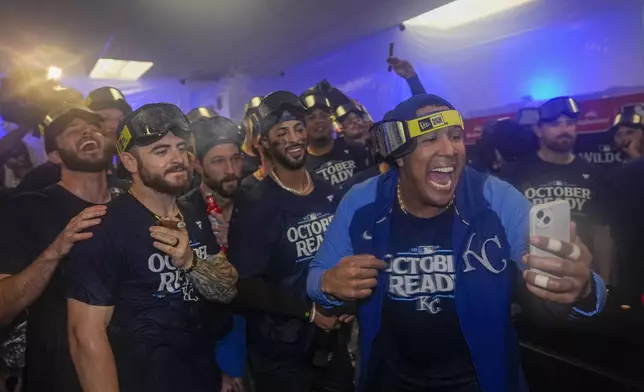 Kansas City Royals catcher Salvador Perez, right, holds a cell phone as he and teammates celebrate after defeating the Baltimore Orioles 2-1 in Game 2 of an AL Wild Card Series baseball game, Wednesday, Oct. 2, 2024 in Baltimore. (AP Photo/Stephanie Scarbrough)