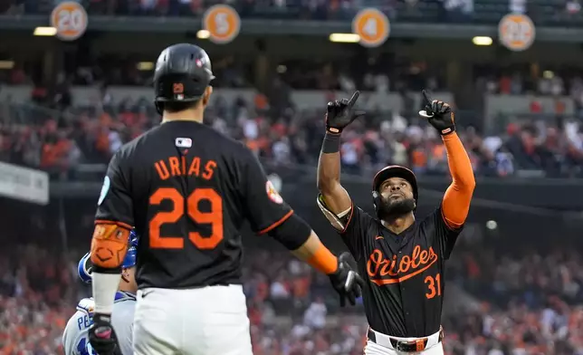 Baltimore Orioles' Cedric Mullins (31), with Ramón Urías (29) looking on, gestures after hitting a solo home run against the Kansas City Royals during the fifth inning in Game 2 of an AL Wild Card Series baseball game, Wednesday, Oct. 2, 2024 in Baltimore. (AP Photo/Stephanie Scarbrough)