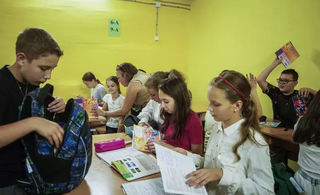 Children from Gymnasium No. 6 spread out their books in a school basement during an air alert in Zaporizhzhia, Ukraine, Sept. 3, 2024. (AP Photo/Evgeniy Maloletka)