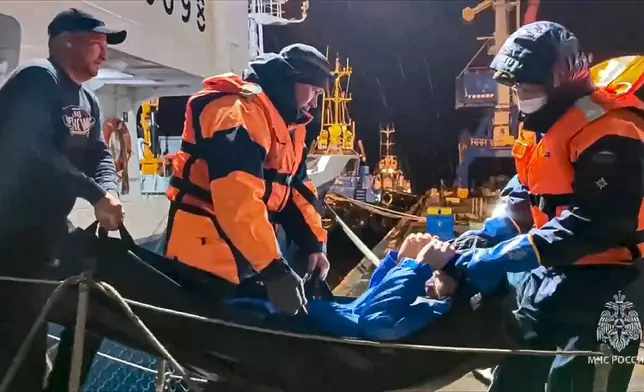 In this photo taken from video released by Russian Emergency Ministry Press Service on Tuesday, Oct. 15, 2024, Russian emergency workers pull Mikhail Pichugin ashore after he was rescued by a fishing vessel following 67 days adrift in the Sea of Okhotsk near the village of Ust-Khairuzovo in Kamchatka region of Russian far east. (Russian Emergency Ministry Press Service via AP)