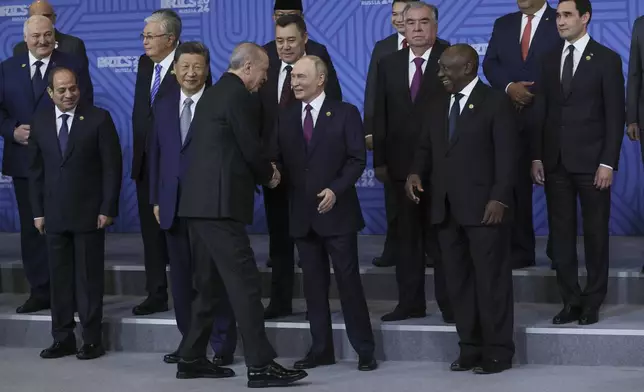 Russian President Vladimir Putin, center, shakes hands with Turkish President Recep Tayyip Erdogan during posing for a family photo prior to Outreach/BRICS Plus format session at the BRICS Summit in Kazan, Russia, Thursday, Oct. 24, 2024. (Maxim Shipenkov, Pool Photo via AP)