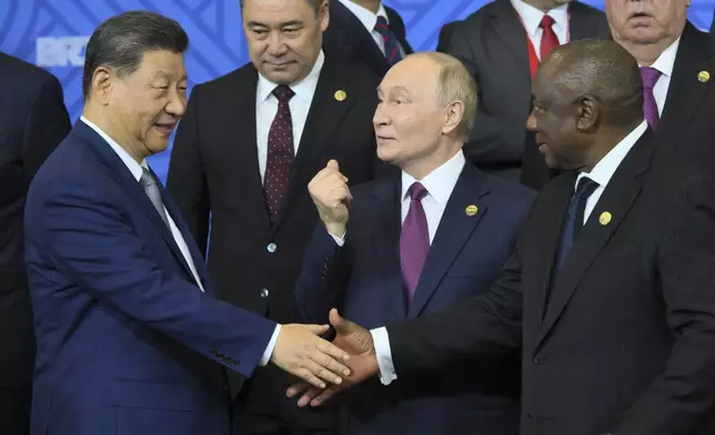 Russian President Vladimir Putin, center, gestures while Chinese President Xi Jinping, left, and South African President Cyril Ramaphosa shake hands during a family photo ceremony prior to Outreach/BRICS Plus format session on the sidelines of the the BRICS summit in Kazan, Russia, Thursday, Oct. 24, 2024. (Grigory Sysoyev/Photo host brics-russia2024.ru via AP)