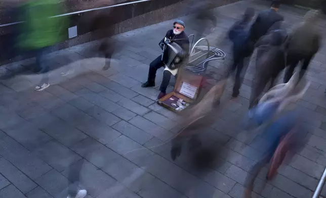 An elderly man plays the accordion in the morning in the hope of getting some small money at the entrance to the subway in Moscow, Russia, Thursday, Oct. 17, 2024. (AP Photo/Alexander Zemlianichenko)