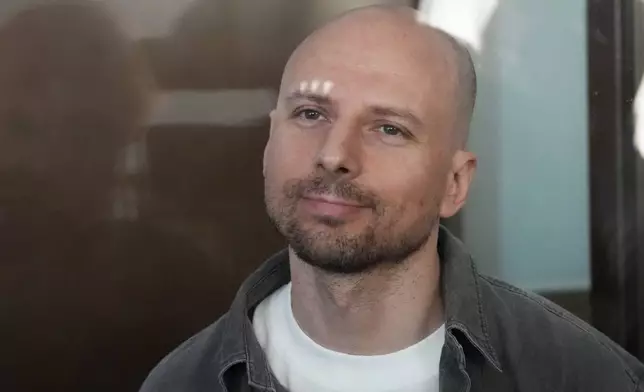 Russian journalist Sergey Karelin accused of working for a group founded by the late Russian opposition politician Alexei Navalny, stands in a defendant's cage of the Nagatinsky District Court in Moscow, Russia, on Wednesday, Oct. 2, 2024. (AP Photo)