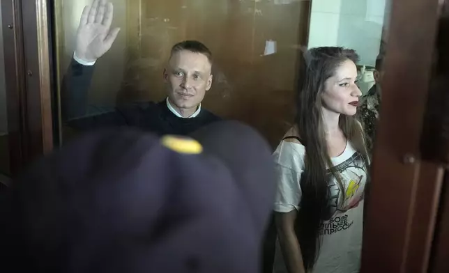 Russian journalists Konstantin Gabov, left, and Antonina Favorskaya, accused of working for a group founded by the late Russian opposition politician Alexei Navalny, stand in a defendant's cage of the Nagatinsky District Court in Moscow, Russia, on Wednesday, Oct. 2, 2024. (AP Photo)