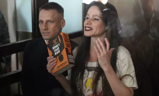 Russian journalists Konstantin Gabov, left, and Antonina Favorskaya, accused of working for a group founded by the late Russian opposition politician Alexei Navalny, stand in a defendant's cage of the Nagatinsky District Court in Moscow, Russia, on Wednesday, Oct. 2, 2024. (AP Photo)