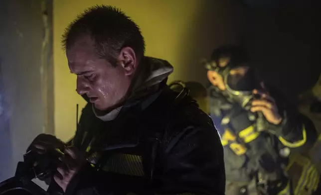 Firefighters wear oxygen masks before entering a floor that burned down after a Russian attack killed a teenager in Kyiv, Ukraine, Friday, Oct. 25, 2024. (AP Photo/Alex Babenko)