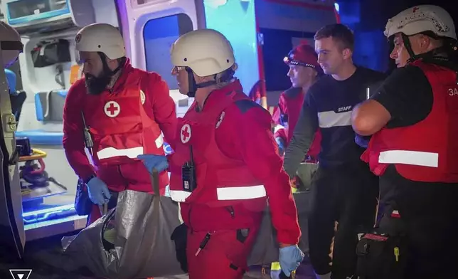 In this photo provided by the Ukrainian Emergency Service, Emergency workers carry a wounded resident after Russian missile attack in Odesa, Ukraine, late Thursday, Oct. 10, 2024. Four Russian missile and drone attacks on the Odesa region this week have killed 14 people and wounded around 20, according to local officials. (Ukrainian Emergency Service via AP)