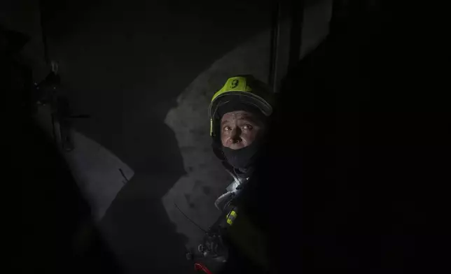 A firefighter looks on from a floor that burned down after a Russian attack killed a teenager in Kyiv, Ukraine, Friday, Oct. 25, 2024. (AP Photo/Alex Babenko)