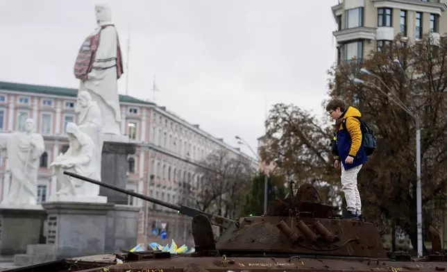 A boy stands on Russian burned APC in central Kyiv, Ukraine, Monday, Oct. 14, 2024. (AP Photo/Alex Babenko)