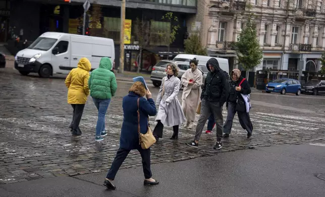 Locals cross a street during rain in Kyiv, Ukraine, Monday, Oct. 14, 2024.(AP Photo/Alex Babenko)