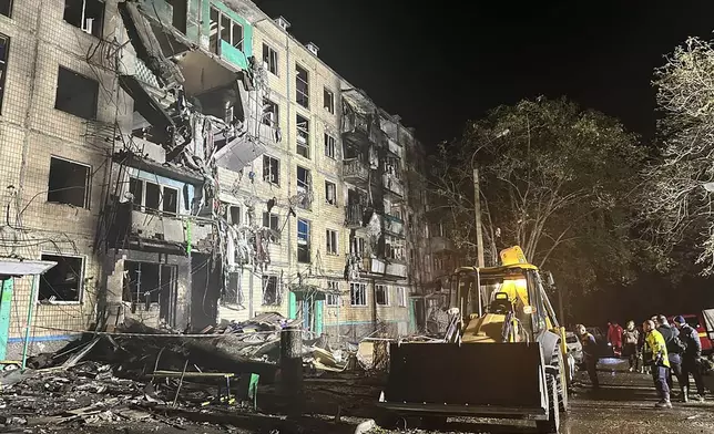 People gather around the damage and debris after a Russian strike on a residential building in Kharkiv, Ukraine, late Wednesday Oct. 2, 2024. (Ukrainian National Police via AP)