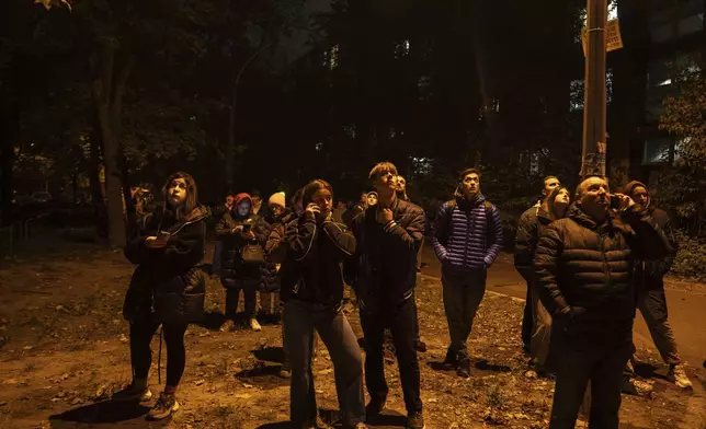 Local residents watch a residential building burn after an attack of Russian drones killed a teenager in Kyiv, Ukraine, Friday, Oct. 25, 2024. (AP Photo/Alex Babenko)