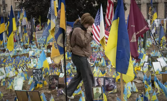 People react during a nationwide minute of silence in memory of fallen soldiers, who defended their homeland in war with Russia, on Defenders Day at the improvised war memorial in Independence square in Kyiv, Ukraine, Tuesday, Oct. 1, 2024. (AP Photo/Efrem Lukatsky)