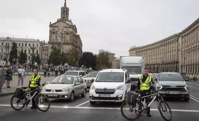 Drivers stop their cars and passerby bow their heads to keep a nationwide minute of silence in memory of fallen soldiers, who defended their homeland in war with Russia, on Defenders Day in Independence square in Kyiv, Ukraine, Tuesday, Oct. 1, 2024. (AP Photo/Efrem Lukatsky)