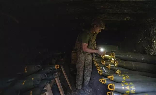 FILE – A serviceman identified only as Oleh of the 148th artillery brigade of Ukraine’s air assault forces prepares 155mm artillery shells before firing them toward Russian positions at the front line in Donetsk region of Ukraine, on Aug. 21, 2024. (AP Photo/Evgeniy Maloletka, File)