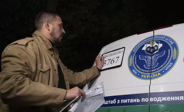 In this photo provided by the Press Service of the President of Ukraine on Oct. 19, 2024, a Ukrainian serviceman changes a plate showing the total sum of 3,767 of POWs and civilians returned after some of them have returned from captivity during a POWs exchange in an undisclosed location, Ukraine. (Press Service of the President of Ukraine via AP)