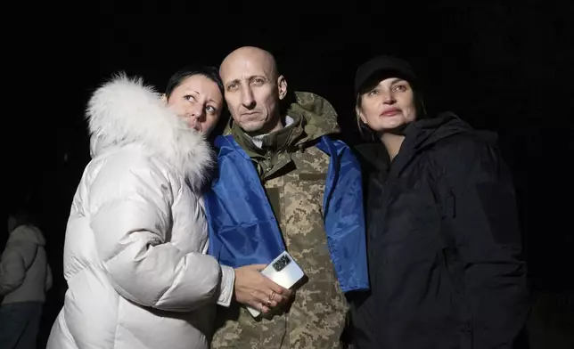 In this photo provided by the Press Service of the President of Ukraine on Oct. 19, 2024, a Ukrainian serviceman hugs his relatives after returning from captivity during a POWs exchange in an undisclosed location, Ukraine. (Press Service of the President of Ukraine via AP)