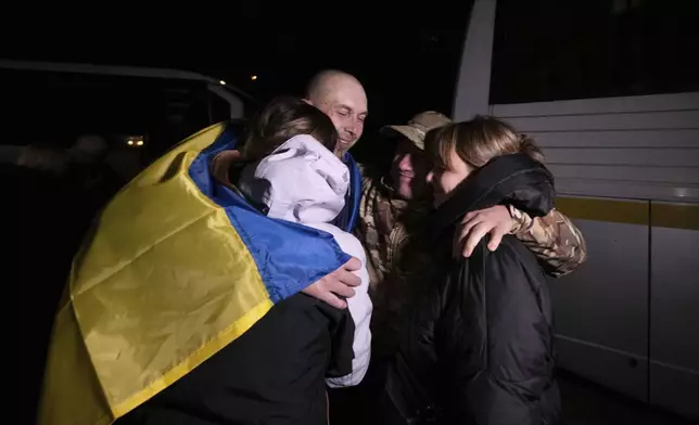 In this photo provided by the Press Service of the President of Ukraine on Oct. 19, 2024, a Ukrainian serviceman hugs his relatives after returning from captivity during a POWs exchange in an undisclosed location, Ukraine. (Press Service of the President of Ukraine via AP)