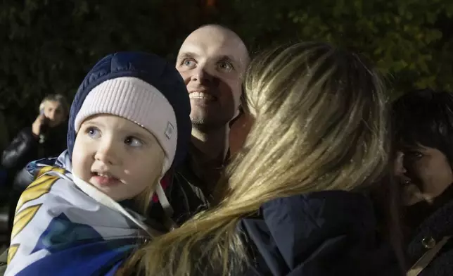 In this photo provided by the Press Service of the President of Ukraine on Oct. 19, 2024, a Ukrainian serviceman hugs his family after returning from captivity during a POWs exchange in an undisclosed location, Ukraine. (Press Service of the President of Ukraine via AP)