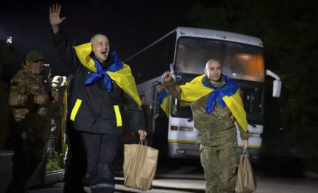 In this photo provided by the Press Service of the President of Ukraine on Oct. 19, 2024, Ukrainian servicemen shout, "Glory to Ukraine," with National flags after returning from captivity during a POWs exchange in an undisclosed location, Ukraine. (Press Service of the President of Ukraine via AP)