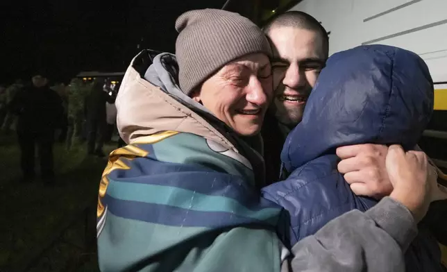 In this photo provided by the Press Service of the President of Ukraine on Oct. 19, 2024, a Ukrainian serviceman hugs his family after returning from captivity during a POWs exchange in an undisclosed location, Ukraine. (Press Service of the President of Ukraine via AP)