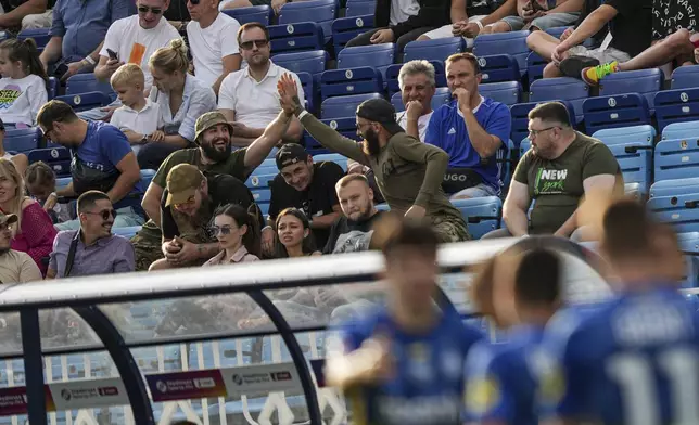 Ukrainian serviceman of Azov Brigade, also known by the call sign "Escobar", center left, celebrates a goal of Dynamo Kyiv during a soccer match with Zorya Luhansk in Kyiv, Ukraine, Saturday Sept. 14, 2024. (AP Photo/Evgeniy Maloletka)