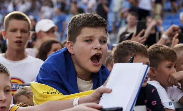 Young fans urge players to sign autographs after a soccer match of Dynamo Kyiv and Zorya Luhansk in Kyiv, Ukraine, Saturday Sept. 14, 2024. (AP Photo/Evgeniy Maloletka)