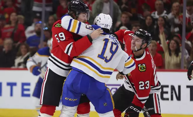 Chicago Blackhawks left wing Tyler Bertuzzi grabs onto Buffalo Sabres center Peyton Krebs jersey after hitting Chicago Blackhawks center Philipp Kurashev during the third period of an NHL hockey game, Saturday, Oct. 19, 2024, in Chicago. (AP Photo/Melissa Tamez)