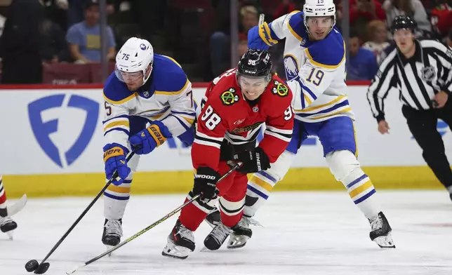 Buffalo Sabres defenseman Connor Clifton steals the puck from Chicago Blackhawks center Connor Bedard during the second period of an NHL hockey game, Saturday, Oct. 19, 2024, in Chicago. (AP Photo/Melissa Tamez)