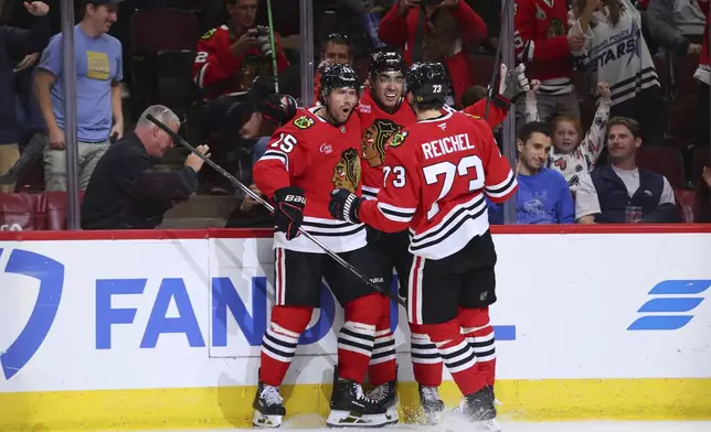 Chicago Blackhawks center Craig Smith, left, celebrates with center Andreas Athanasiou, middle, and left wing Lukas Reichel during the second period of an NHL hockey game against the Buffalo Sabres, Saturday, Oct. 19, 2024, in Chicago. (AP Photo/Melissa Tamez)