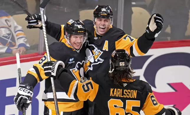 Pittsburgh Penguins' Sidney Crosby (87) celebrates his game-winning goal in overtime with Evgeni Malkin (71) and Erik Karlsson (65) during an NHL hockey game against the Buffalo Sabres in Pittsburgh, Wednesday, Oct. 16, 2024. (AP Photo/Gene Puskar)