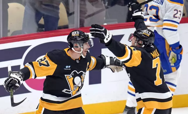 Pittsburgh Penguins' Sidney Crosby (87) celebrates his game-winning goal in overtime with Evgeni Malkin during an NHL hockey game against the Buffalo Sabres in Pittsburgh, Wednesday, Oct. 16, 2024. (AP Photo/Gene Puskar)