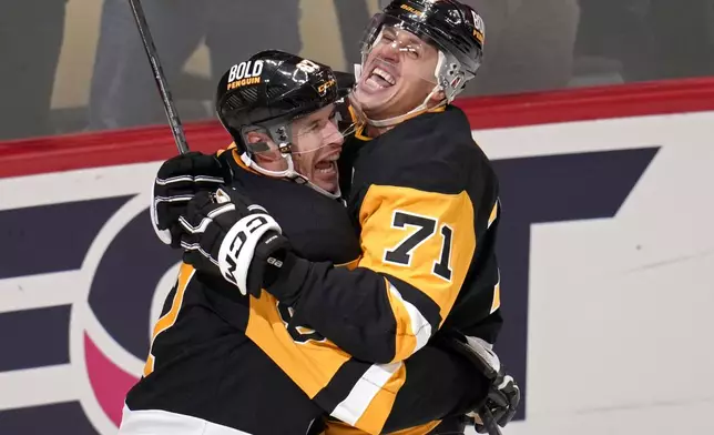 Pittsburgh Penguins' Sidney Crosby (87) celebrates his game-winning goal in overtime with Evgeni Malkin during an NHL hockey game against the Buffalo Sabres in Pittsburgh, Wednesday, Oct. 16, 2024. (AP Photo/Gene Puskar)