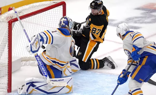 Pittsburgh Penguins' Sidney Crosby (87) gets a shot behind Buffalo Sabres goaltender Ukko-Pekka Luukkonen (1) for the game-winning goal in overtime during an NHL hockey game in Pittsburgh, Wednesday, Oct. 16, 2024. (AP Photo/Gene Puskar)