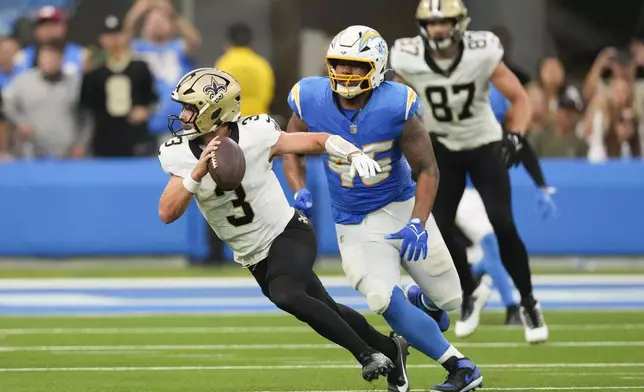 New Orleans Saints quarterback Jake Haener (3) scrambled from Los Angeles Chargers linebacker Tuli Tuipulotu (45) in the second half of an NFL football game in Inglewood, Calif., Sunday, Oct. 27, 2024. (AP Photo/Mark J. Terrill)