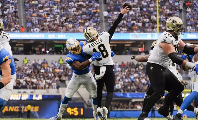 New Orleans Saints quarterback Spencer Rattler (18) is hit by Los Angeles Chargers linebacker Daiyan Henley (0) as he releases the ball in the second half of an NFL football game in Inglewood, Calif., Sunday, Oct. 27, 2024. (AP Photo/Mark J. Terrill)