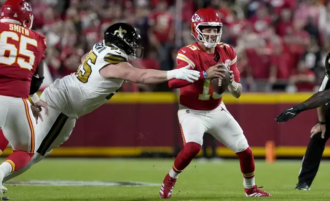 Kansas City Chiefs quarterback Patrick Mahomes, right, scrambles away from New Orleans Saints defensive tackle John Ridgeway III during the first half of an NFL football game Monday, Oct. 7, 2024, in Kansas City, Mo. (AP Photo/Ed Zurga)