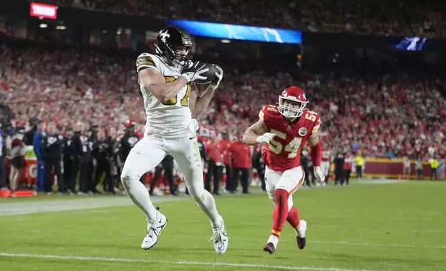 New Orleans Saints tight end Foster Moreau, left, catches a touchdown pass as Kansas City Chiefs linebacker Leo Chenal (54) defends during the second half of an NFL football game Monday, Oct. 7, 2024, in Kansas City, Mo. (AP Photo/Ed Zurga)