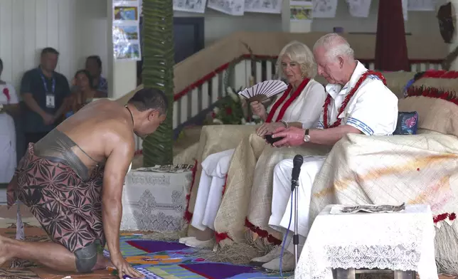 Britain's King Charles III, right, accepts a cup of kava, locally known as "ava," as Queen Camilla looks on during an ava ceremony to welcome royals at Moata village in Samoa's capital Apia, Thursday, Oct. 24, 2024. (Manaui Faulalo/Pool Photo via AP)