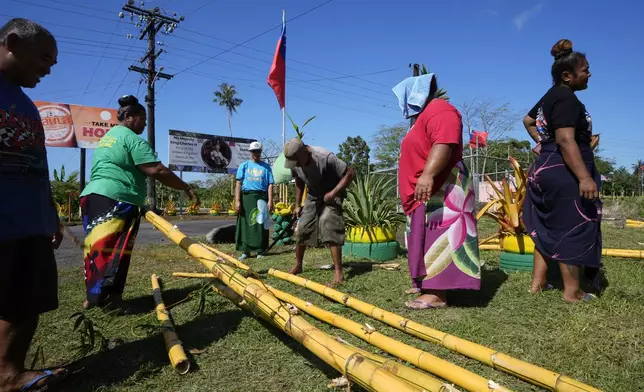 People from the village of Siumu, Samoa, work on decorating the entrance of their village on Monday, Oct. 21, 2024, as they prepare for the arrival of King Charles III. (AP Photo/Rick Rycroft)