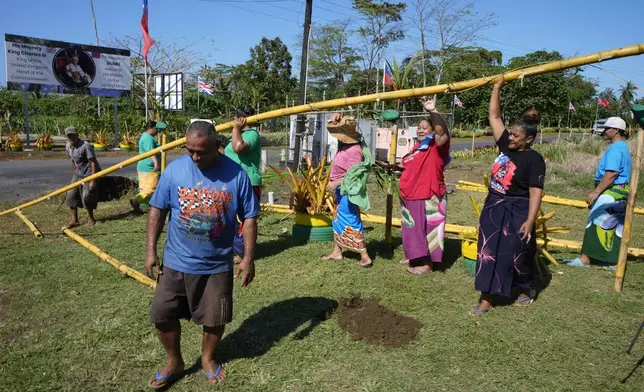 People from the village of Siumu, Samoa, work on decorating the entrance of their village on Monday, Oct. 21, 2024, as they prepare for the arrival of King Charles III. (AP Photo/Rick Rycroft)