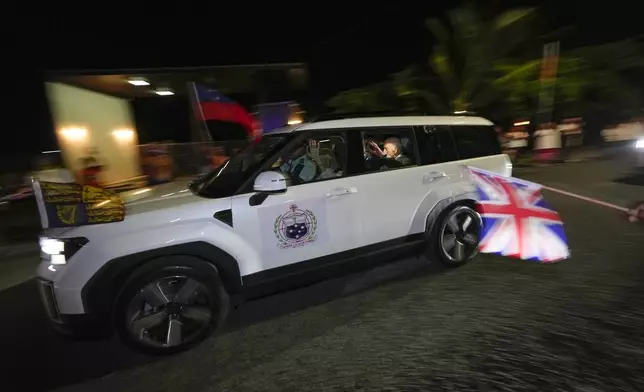 Britain's King Charles III and Queen Camilla wave as they arrive in the village of Siumu, Samoa, on Wednesday, Oct. 23, 2024. (AP Photo/Rick Rycroft)