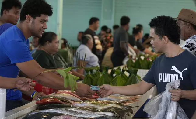 A person pays for his purchase at the fish market in Apia, Samoa, on Sunday, Oct. 20, 2024. (AP Photo/Rick Rycroft)