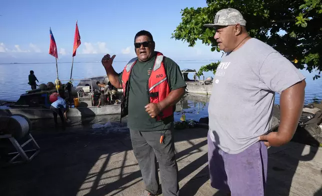 Fishermen Taula Fagatuai, left, and Faalogo Afereti Taliulu talk on Tuesday, Oct. 22, 2024, about the New Zealand navy ship HMNZS Manawanui that sank not far from them in the village of Siumu, Samoa. (AP Photo/Rick Rycroft)